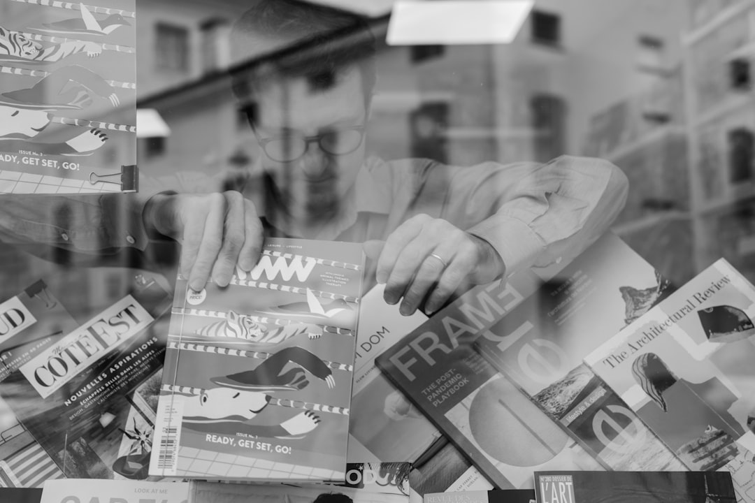 a-man-holding-a-magazine-in-front-of-a-window-jafu5ywddow